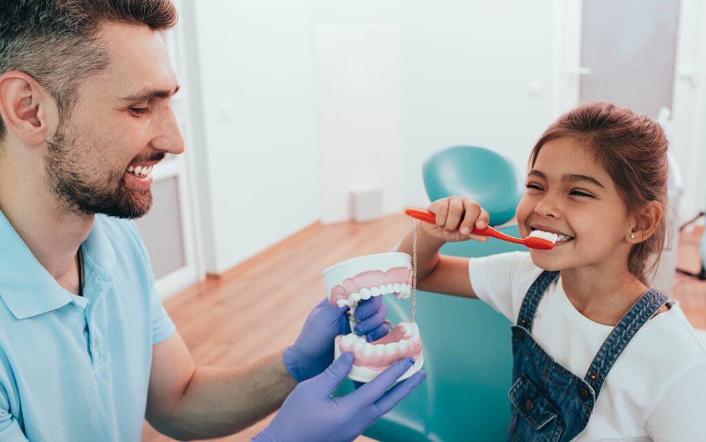 Dentista enseñando a una niña a cepillarse los dientes correctamente en clínica dental de San Pedro del Pinatar